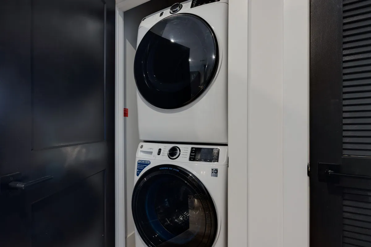 A stacked washer and dryer unit, representing in-unit laundry conveniences within a modern and tidy living space.